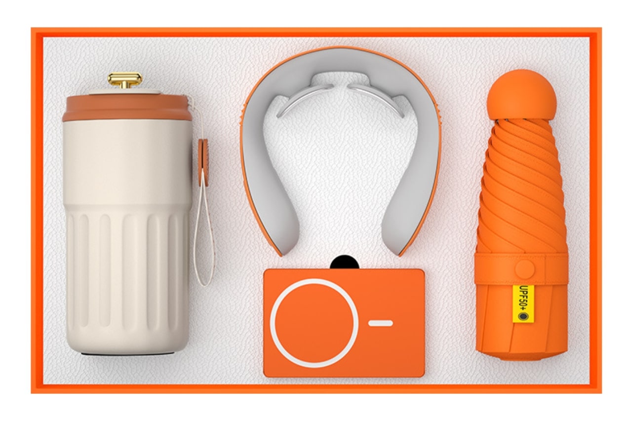 A neatly arranged custom promotional gift set featuring a beige and orange thermos, an orange neck massager, an orange wireless speaker, and a compact orange umbrella, all laid out in an orange-bordered box.