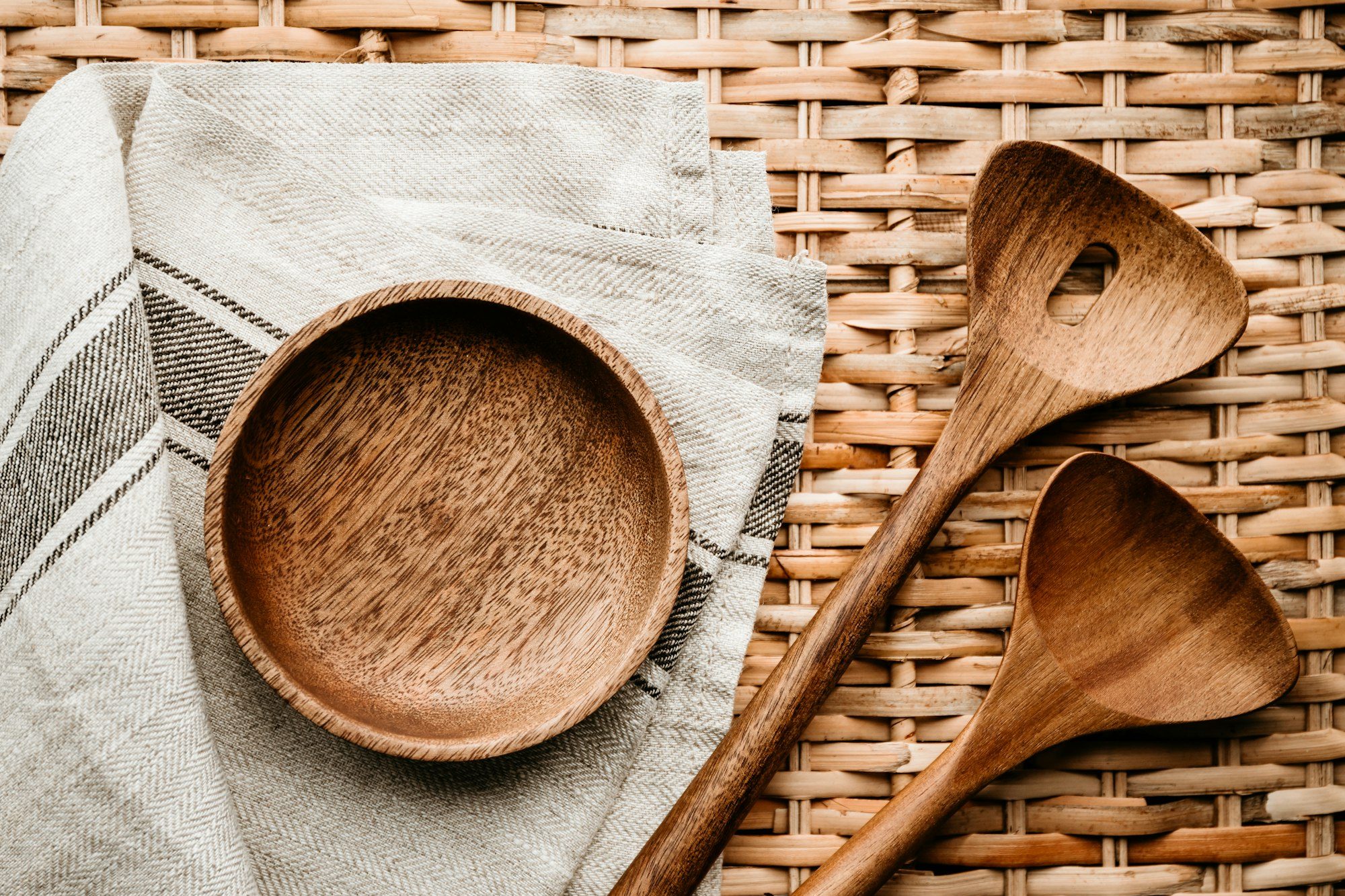 Cooking eco style background. Wooden kitchen tools and bowl on a rattan.