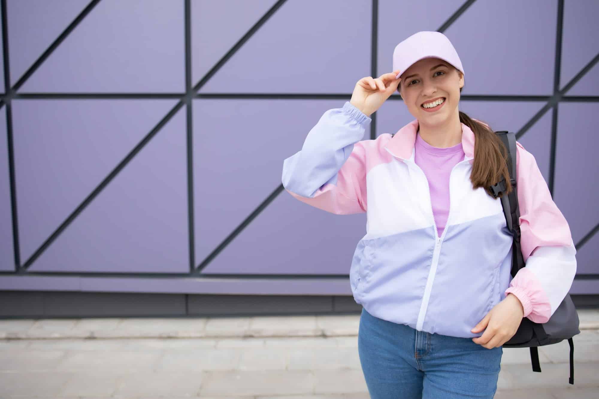 Happy young woman in lilac baseball cap, jacket. Jeans