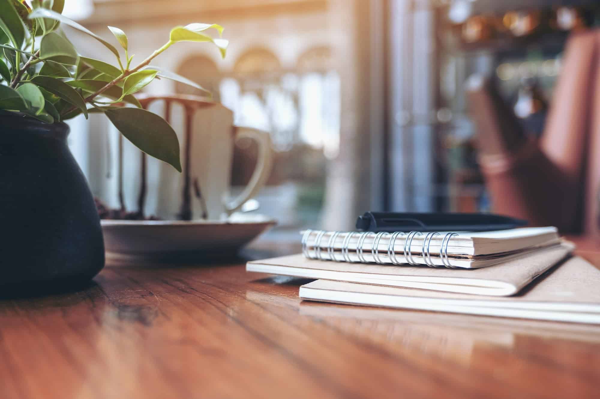 Notebooks, pen and coffee cup on wooden table